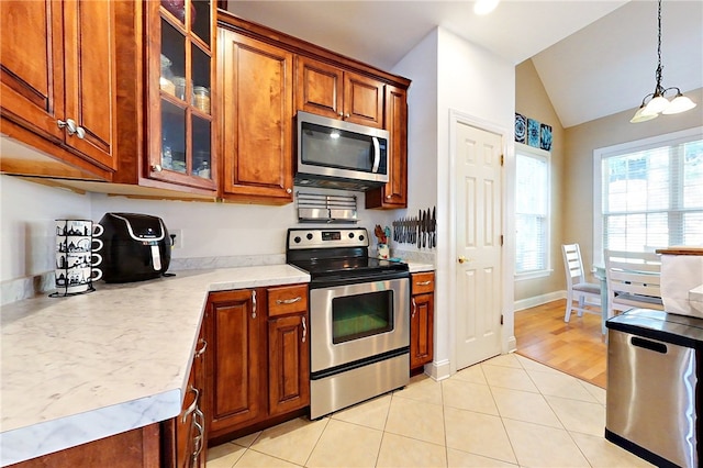 kitchen with a notable chandelier, decorative light fixtures, lofted ceiling, light tile patterned flooring, and appliances with stainless steel finishes