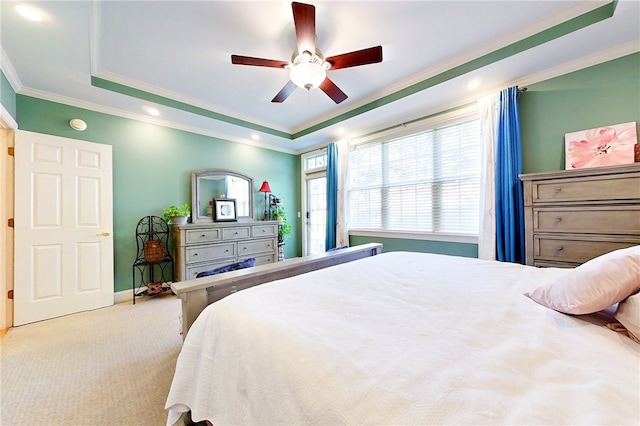 bedroom featuring ceiling fan, light colored carpet, crown molding, and a tray ceiling