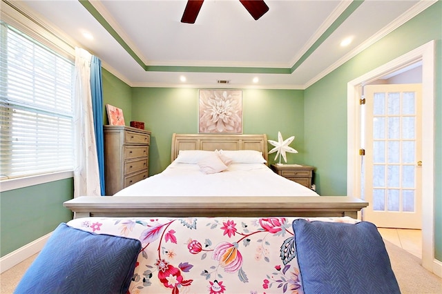 bedroom with a raised ceiling, ceiling fan, crown molding, and light colored carpet