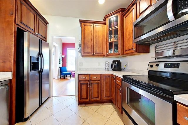 163 N Cottages Dr, Saint Simons Island, GA 31522 - kitchen featuring stainless steel appliances, light countertops, brown cabinets, and glass insert cabinets