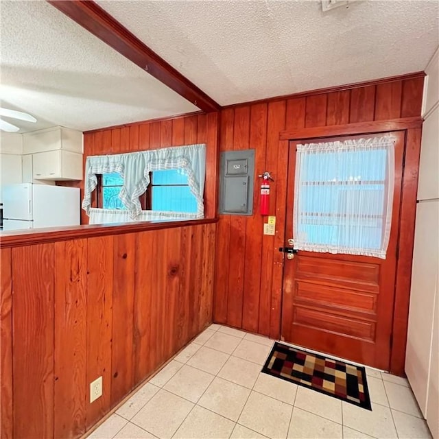 interior space with beam ceiling, light tile patterned flooring, wooden walls, a textured ceiling, and electric panel