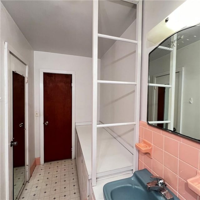 bathroom featuring a sink, tile walls, and tile patterned floors