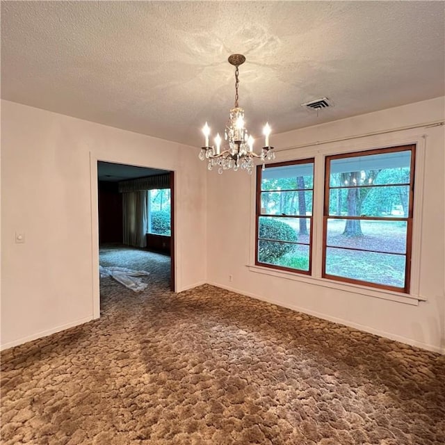 carpeted spare room featuring baseboards, a textured ceiling, visible vents, and a notable chandelier