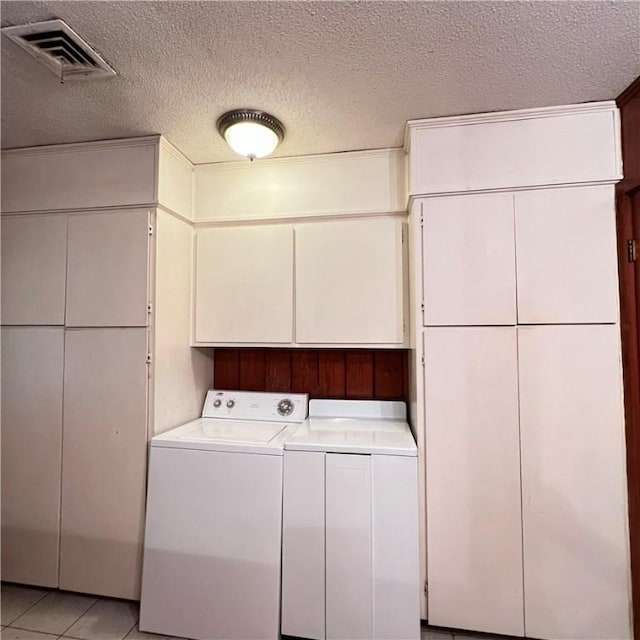 laundry area with cabinet space, visible vents, a textured ceiling, and light tile patterned flooring