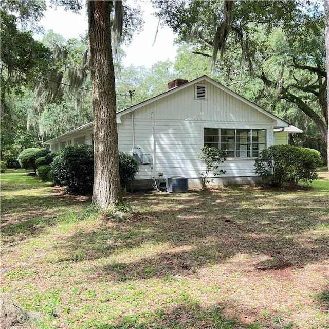 view of side of property with a lawn and cooling unit