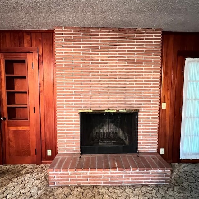 interior details featuring a fireplace, wooden walls, and a textured ceiling