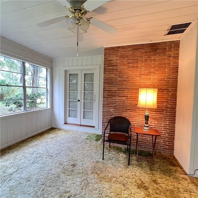 sitting room featuring visible vents, brick wall, ceiling fan, carpet flooring, and french doors