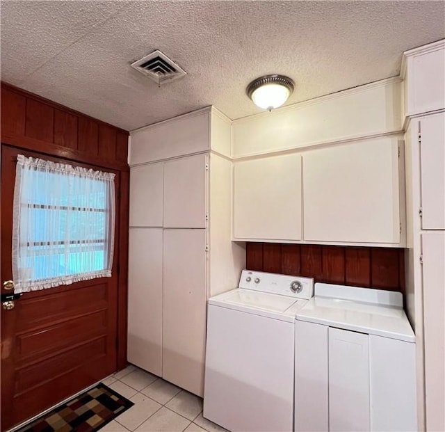 clothes washing area with cabinet space, light tile patterned floors, visible vents, and a textured ceiling