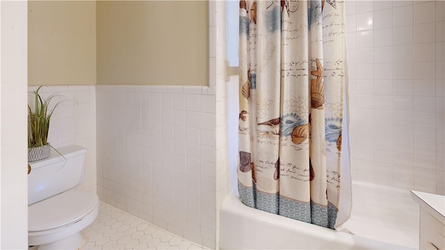 full bathroom with tile patterned floors, toilet, shower / bath combo with shower curtain, vanity, and tile walls