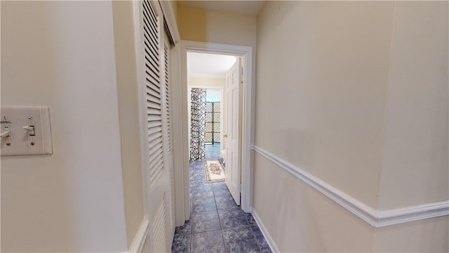 hall featuring dark tile patterned flooring and crown molding