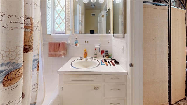 bathroom featuring vanity, curtained shower, tile walls, and tasteful backsplash