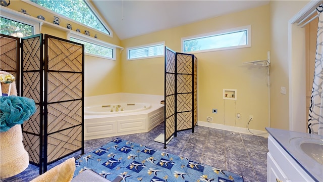 bathroom with vanity, a healthy amount of sunlight, a bath, and vaulted ceiling