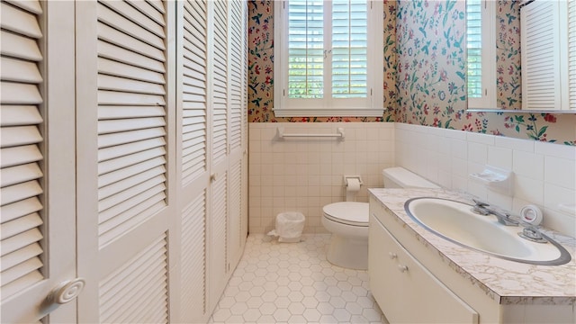 bathroom with tile patterned floors, vanity, toilet, and tile walls