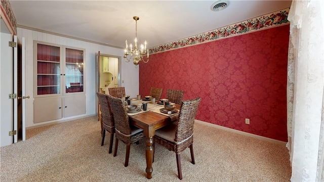 carpeted dining room featuring a chandelier and crown molding