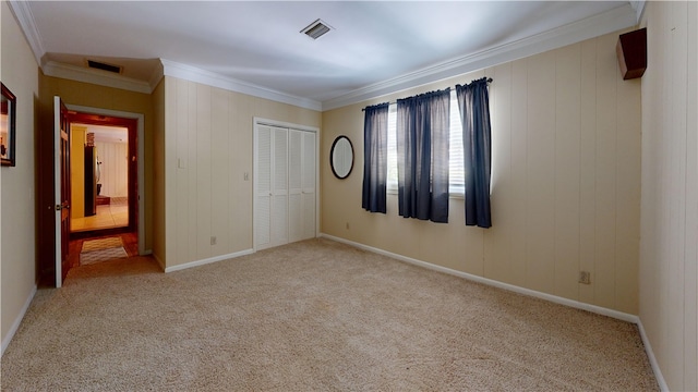 unfurnished bedroom with light colored carpet, ornamental molding, and a closet