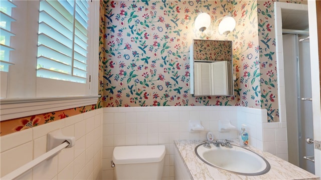 bathroom featuring walk in shower, vanity, tile walls, and toilet