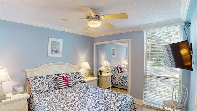 bedroom featuring a textured ceiling, ceiling fan, crown molding, light hardwood / wood-style flooring, and a closet