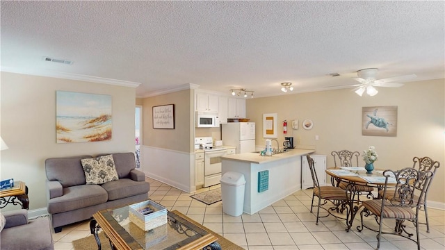 living room with ceiling fan, sink, light tile patterned floors, and a textured ceiling