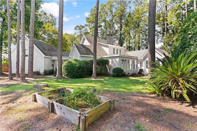 104 Augusta, Saint Simons Island, GA 31522 - exterior space with a front lawn, stucco siding, a vegetable garden, and a chimney