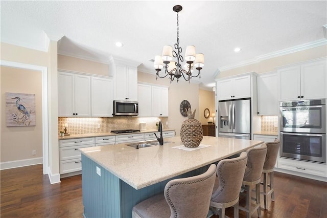 kitchen featuring stainless steel appliances, ornamental molding, an island with sink, and a sink