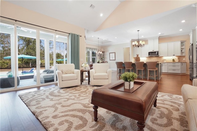 living area featuring recessed lighting, vaulted ceiling, a notable chandelier, and wood finished floors