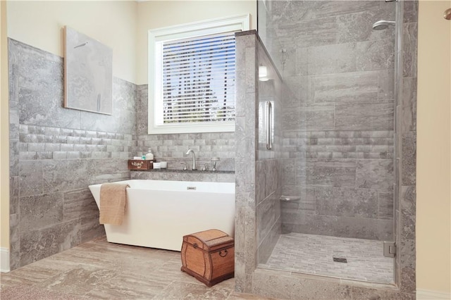 bathroom featuring tile walls, a freestanding tub, and a shower stall