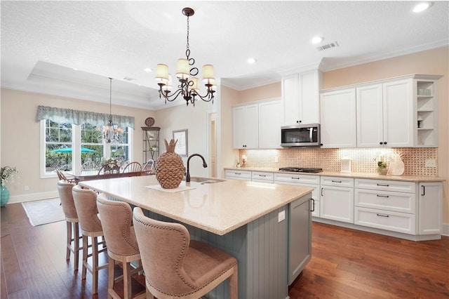 kitchen featuring a chandelier, gas cooktop, a sink, tasteful backsplash, and stainless steel microwave