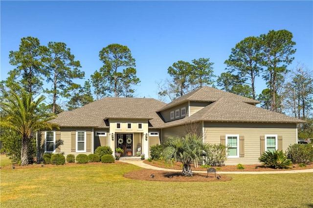 view of front facade featuring a shingled roof and a front yard