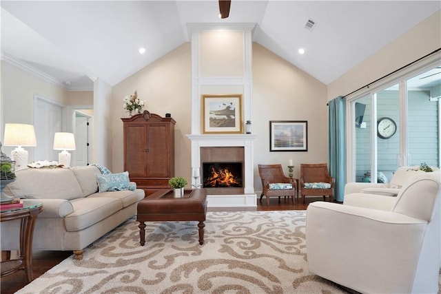 living room featuring lofted ceiling, visible vents, a lit fireplace, and wood finished floors