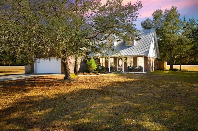 view of front of home featuring driveway, an attached garage, metal roof, and a front yard