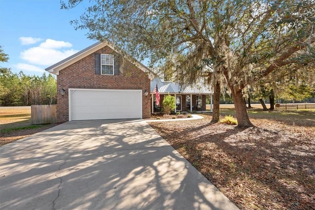 view of front of property with metal roof, a garage, brick siding, fence, and driveway