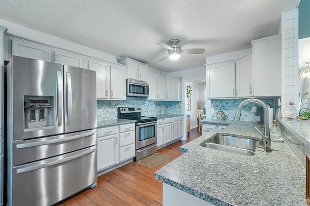 kitchen featuring dark wood finished floors, tasteful backsplash, appliances with stainless steel finishes, white cabinetry, and a sink