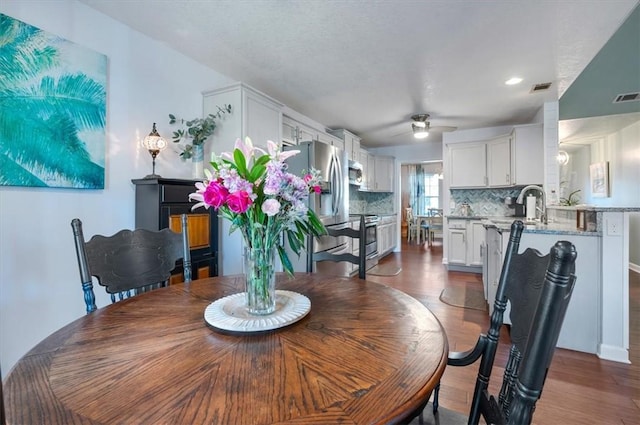 dining area with ceiling fan, dark wood-style flooring, and visible vents