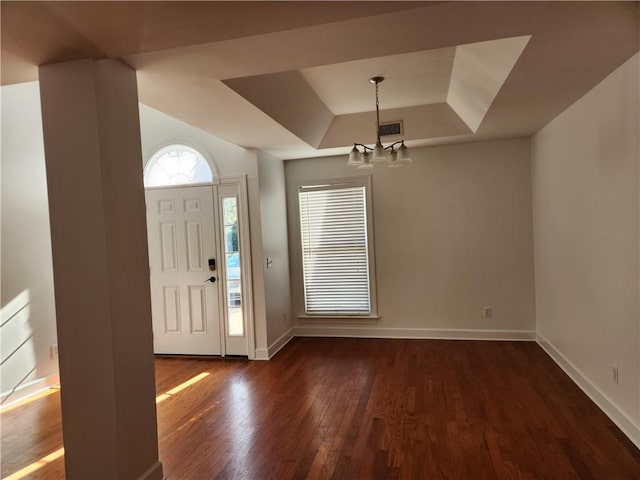 entrance foyer featuring a raised ceiling, dark wood-type flooring, and a chandelier