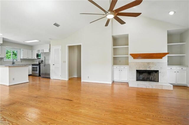 310 Peachtree St, Saint Simons Island, GA 31522 - unfurnished living room featuring a ceiling fan, a fireplace, light wood-type flooring, built in features, and high vaulted ceiling