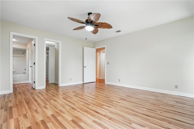 310 Peachtree St, Saint Simons Island, GA 31522 - unfurnished bedroom with light wood-style floors, a walk in closet, ensuite bathroom, a ceiling fan, and a closet