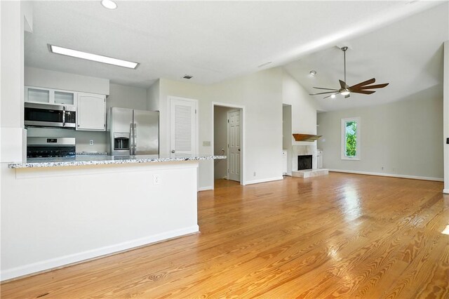 310 Peachtree St, Saint Simons Island, GA 31522 - kitchen featuring stainless steel appliances, ceiling fan, white cabinets, light stone countertops, and light wood-style flooring