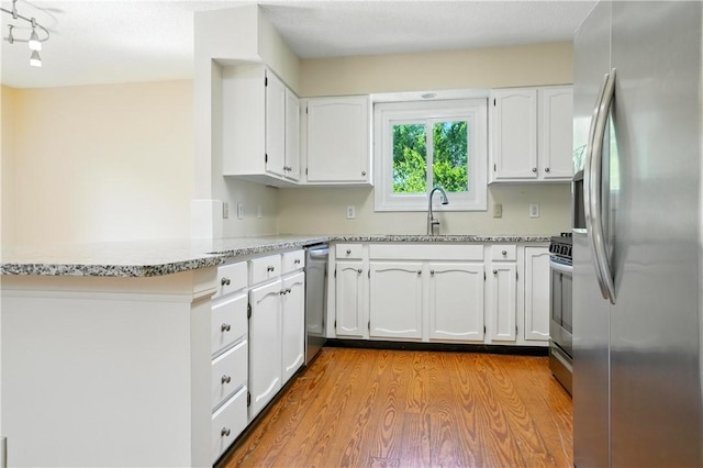 310 Peachtree St, Saint Simons Island, GA 31522 - kitchen featuring stainless steel appliances, light wood-style flooring, white cabinetry, and a peninsula