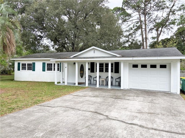 single story home featuring a front yard, concrete block siding, a porch, an attached garage, and concrete driveway