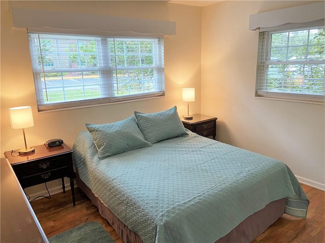 bedroom with baseboards, multiple windows, and wood finished floors