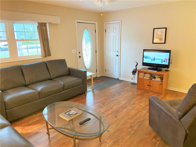 living area featuring a ceiling fan, wood finished floors, and baseboards