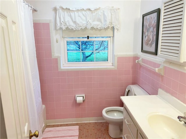 bathroom with tile patterned flooring, curtained shower, tile walls, toilet, and vanity