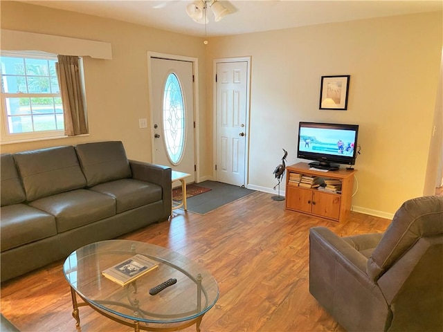 living area with baseboards, a healthy amount of sunlight, wood finished floors, and a ceiling fan