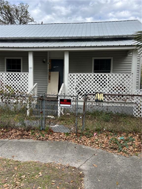 1416 Albany St, Brunswick, GA 31520 - view of front of house with a fenced front yard, metal roof, and covered porch