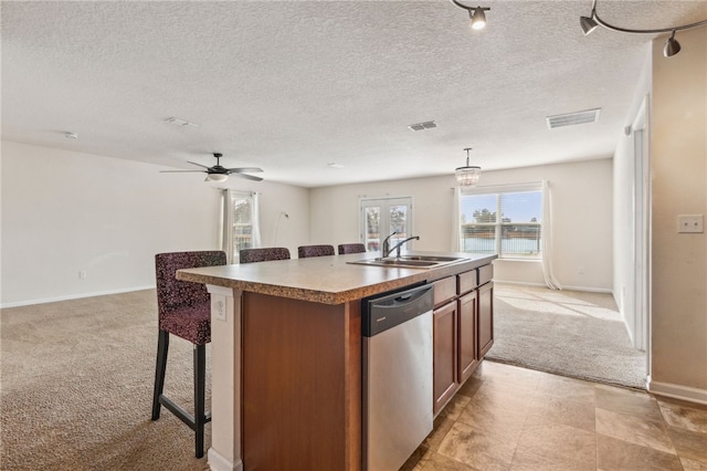 kitchen featuring sink, a center island with sink, dishwasher, pendant lighting, and light colored carpet