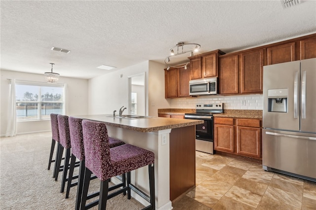 kitchen with sink, a kitchen bar, decorative backsplash, a kitchen island with sink, and stainless steel appliances