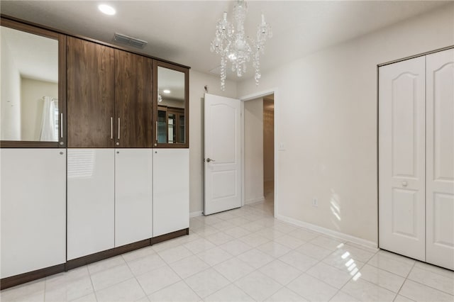 unfurnished bedroom featuring a chandelier, a closet, and light tile patterned floors