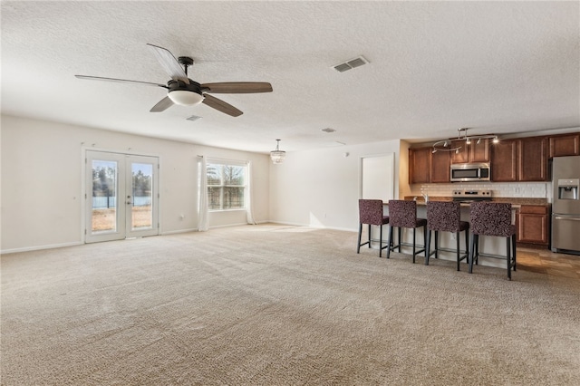 living room with ceiling fan, light carpet, and a textured ceiling