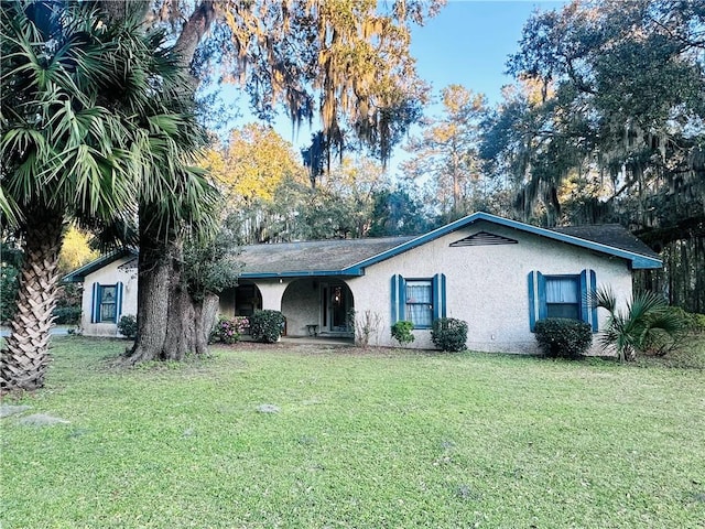 ranch-style home with stucco siding and a front yard