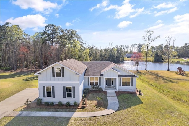 view of front of home featuring a front yard, board and batten siding, a water view, and a shingled roof